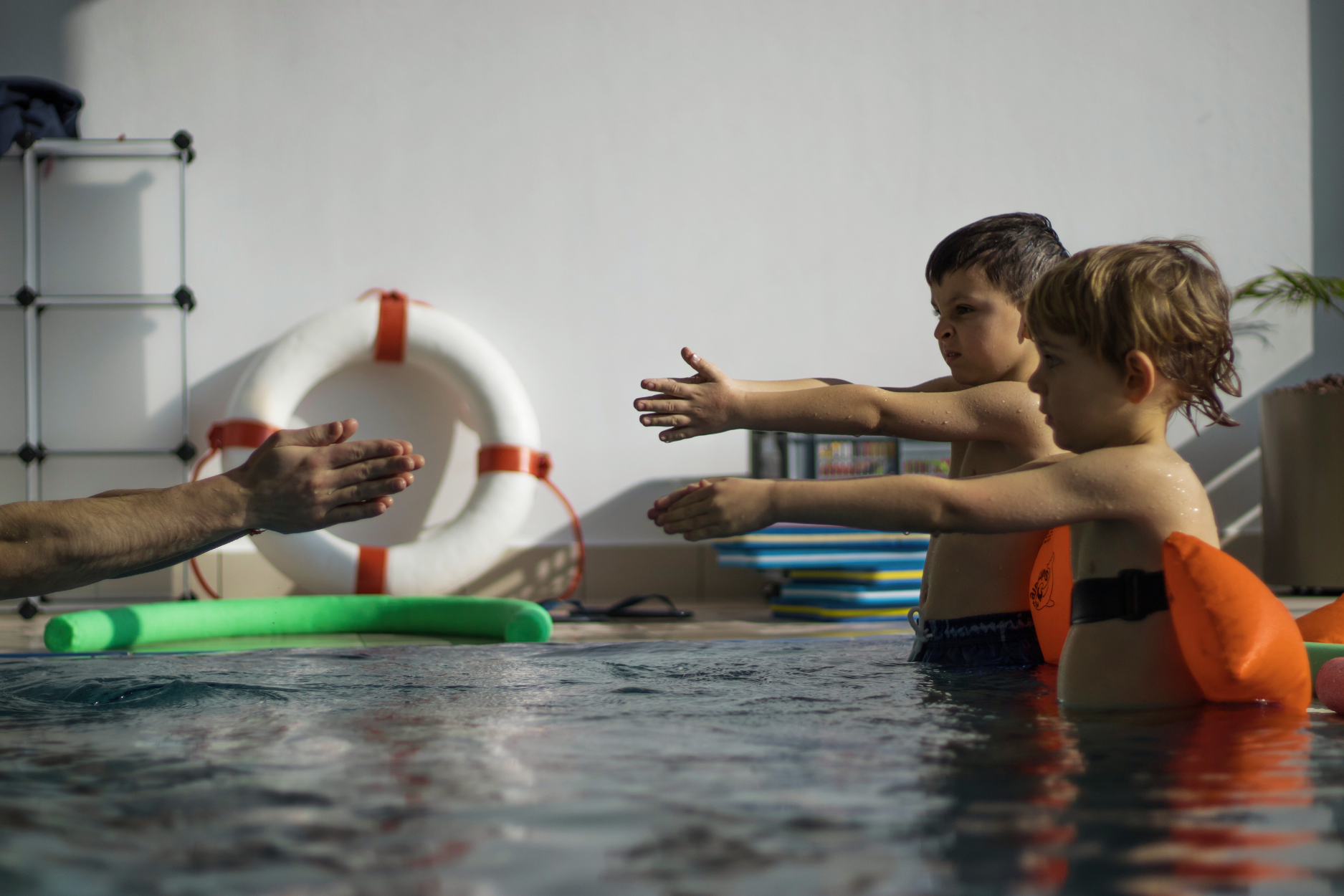 Motorik zwei Kinder üben eine Motorikübung im Schwimmbecken