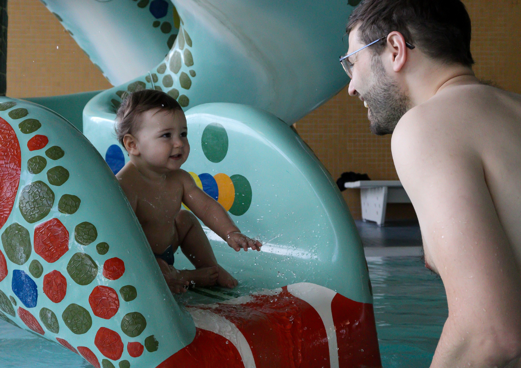 Mama und Baby im Wasser- beide schauen sich an, das Baby hält den Mund weit geöffnet.