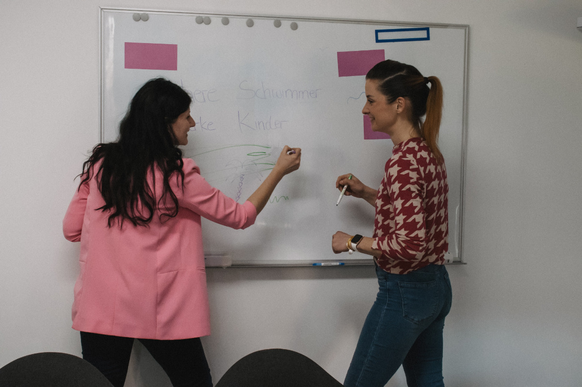 zwei Mitarbeiterinnen schreiben an ein Whiteboard