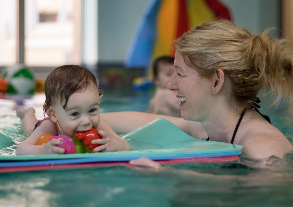 Mutter und Kind beim Babyschwimmen auf einer Matte.