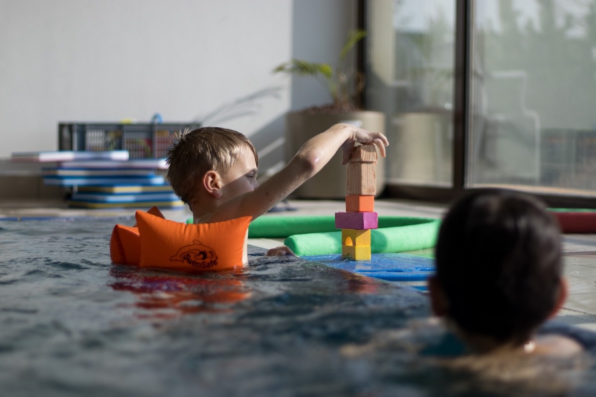 ein Junge baut im Schwimmbecken einen Turm aus Bauklötzen