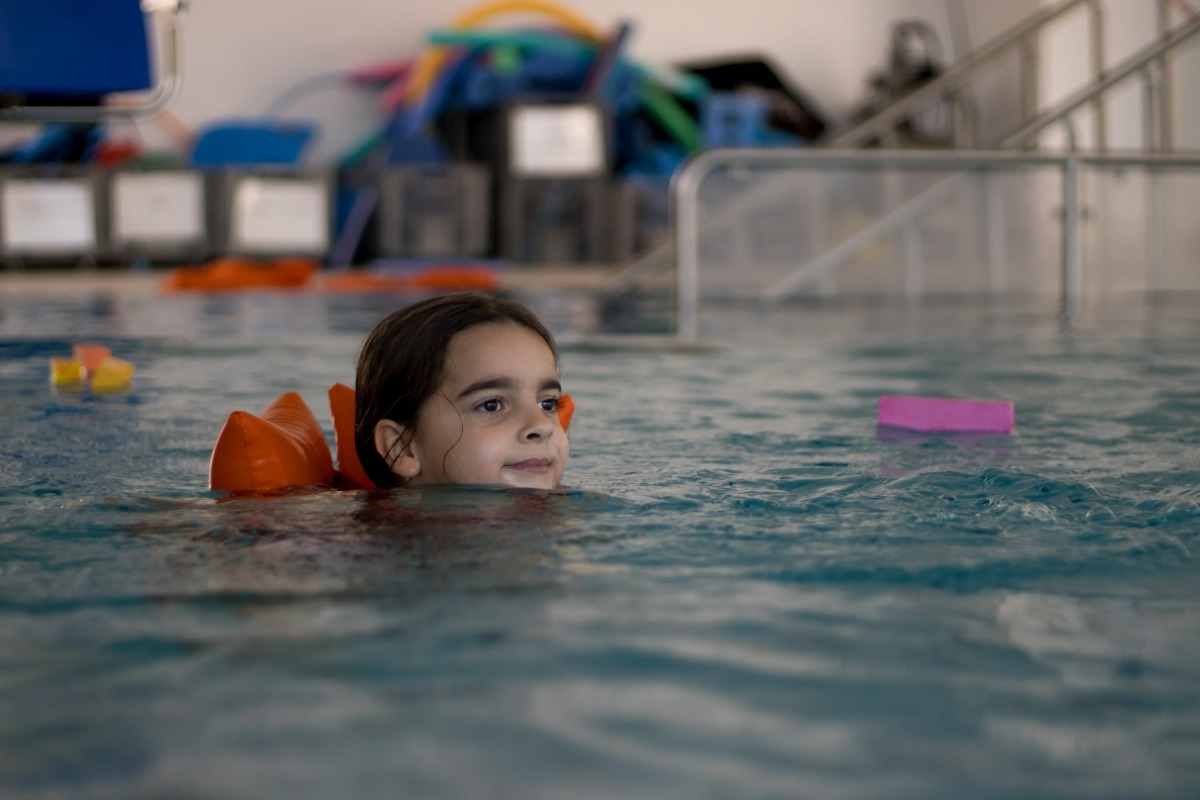 ein Mädchen schwimmt in einem Schwimmbecken mit Schwimmkissen