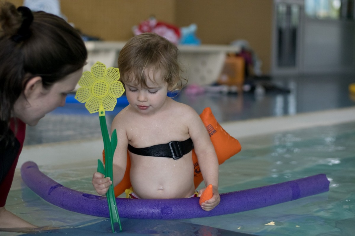 die Kursleiterin spielt mit einem Kind im Wasser Blumen pflanzen