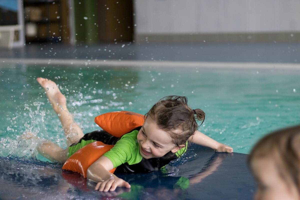 Kind liegt auf einer Schwimmmatte und strampelt mit den Füßen