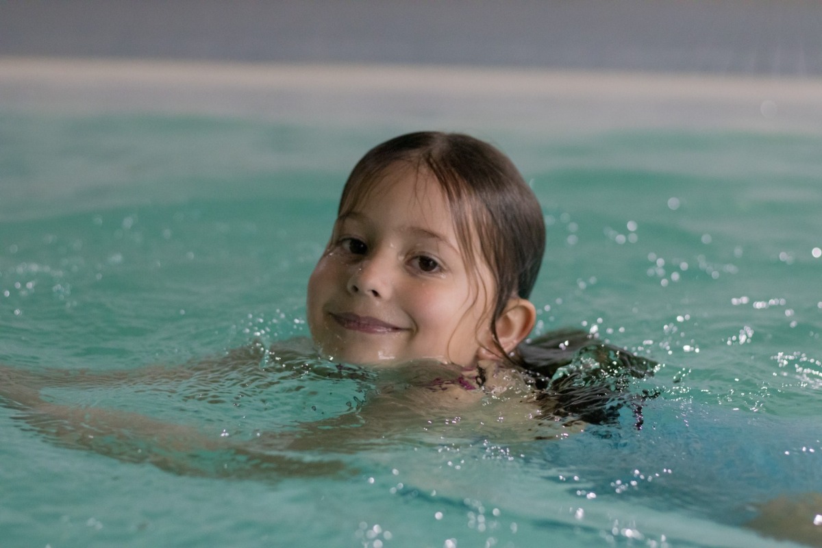 Mädchen schwimmt und lächelt dabei