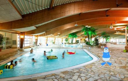 Schwimmen lernen im schönen Badeparadies Eiswiese, wellenförmige Holzdecke, Palmen im Hintergrund und viele Spielgegenstände in einem runden Schwimmbecken