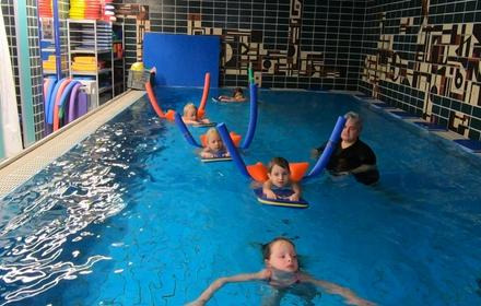 Kinder beim Schwimmunterricht mit Nudel und Brett