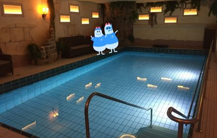 In der Mitte das Schwimmbecken mit einer Leiter zum Einstieg, am Rand eine gemütliche Beleuchtung und Sofas am Beckenrand
