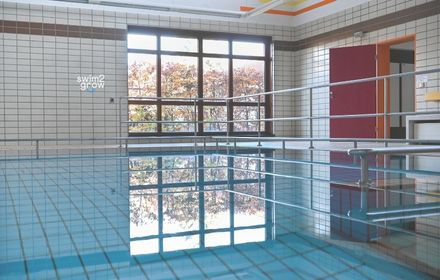 Schwimmenlernen im Bewegungsbad Jabbok, heller Raum, im Hintergrund ein großes Fenster und eine rote Türe