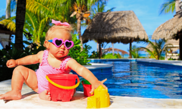 ein süßes speckiges Kind vor einer Urlaubskulisse am Wasser