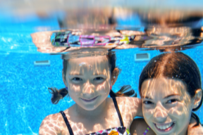 zwei Kinder lächeln unter Wasser in die Kamera