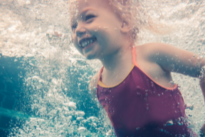 ein Kleinkind unter Wasser, welches lächelt