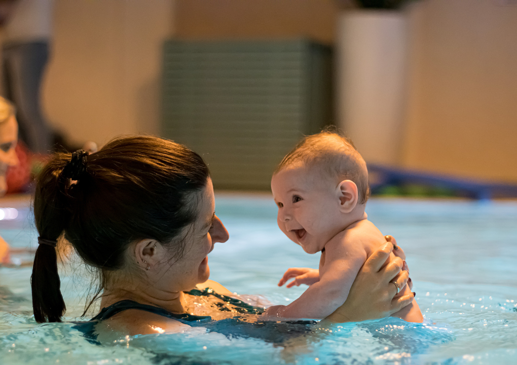 Das Baby genießt sichtlich die Zeit beim Babyschwimmen in Begleitung seiner Mutter.