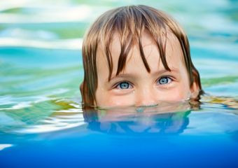 Sport für schüchterne Kinder Der Kopf eines Kindes, das im Wasser taucht, der Mund des Kindes ist unter Wasser getaucht.